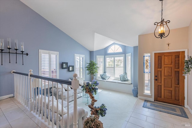 foyer entrance featuring light tile patterned floors, baseboards, and high vaulted ceiling