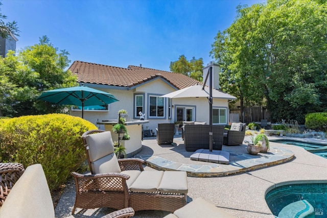 rear view of property with a fenced in pool, a patio, a tiled roof, fence, and an outdoor living space