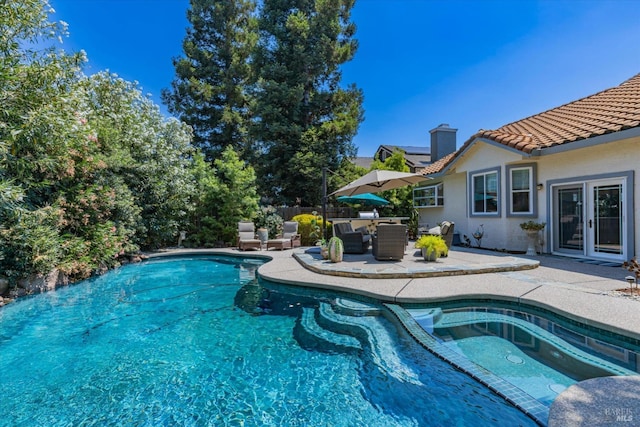 view of swimming pool featuring a pool with connected hot tub, fence, and a patio