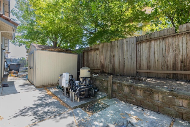 view of patio with an outbuilding, a fenced backyard, and a storage unit