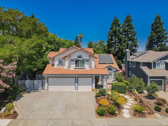 view of front facade featuring a garage, solar panels, fence, driveway, and a tiled roof