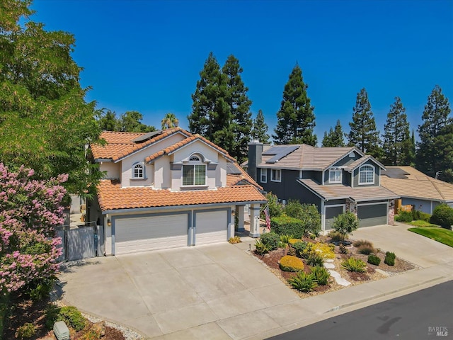 view of front of property featuring concrete driveway, a tile roof, an attached garage, roof mounted solar panels, and stucco siding