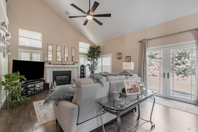 living room featuring dark wood-style flooring, french doors, ceiling fan, high vaulted ceiling, and a tile fireplace