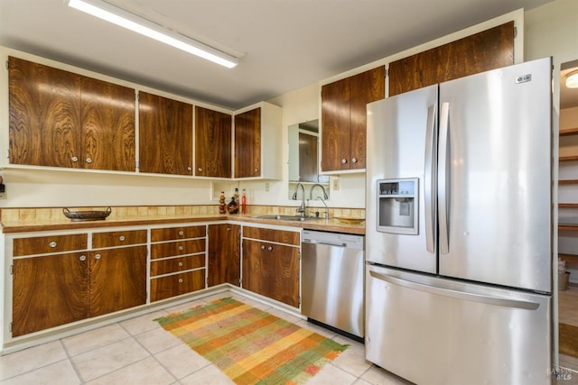 kitchen with light tile patterned floors, light countertops, appliances with stainless steel finishes, and a sink