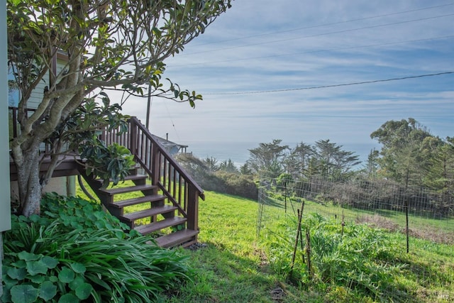 view of yard featuring stairway, a water view, and fence