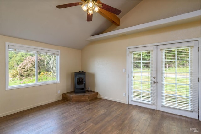 unfurnished living room with baseboards, wood finished floors, a wood stove, vaulted ceiling with beams, and french doors