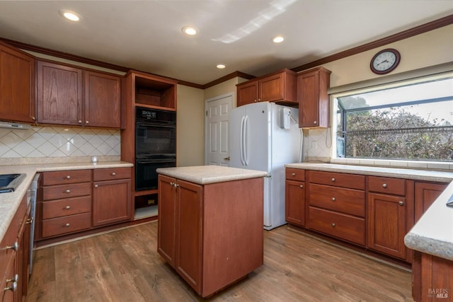 kitchen featuring dobule oven black, freestanding refrigerator, a center island, dark wood finished floors, and crown molding