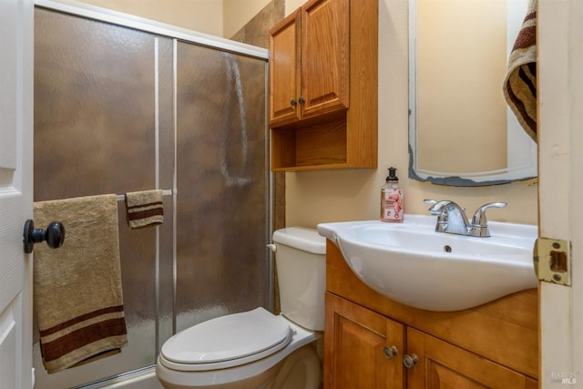 bathroom with a shower stall, toilet, and vanity