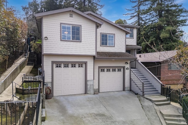 view of front of house featuring concrete driveway, fence, stairway, and an attached garage