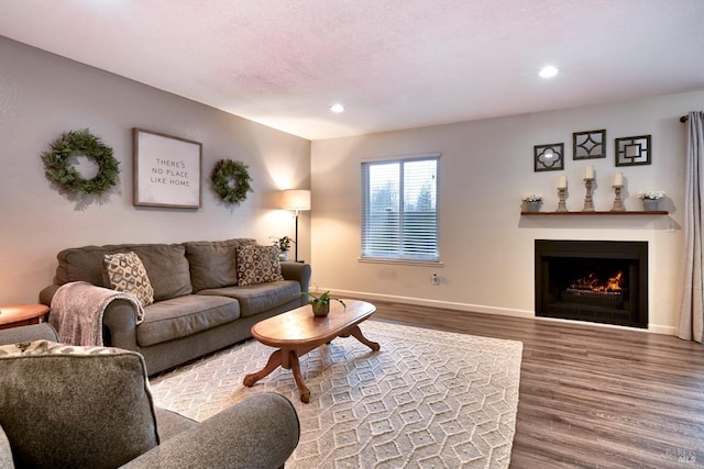 living room with a lit fireplace, recessed lighting, wood finished floors, and baseboards
