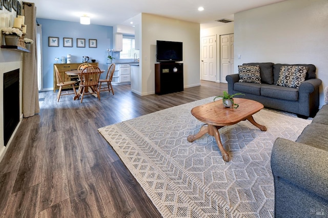 living room featuring recessed lighting, a fireplace, wood finished floors, and baseboards