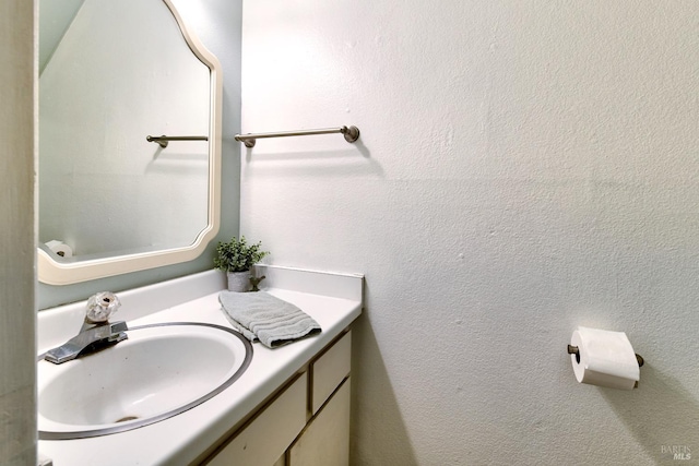 bathroom with a textured wall and vanity