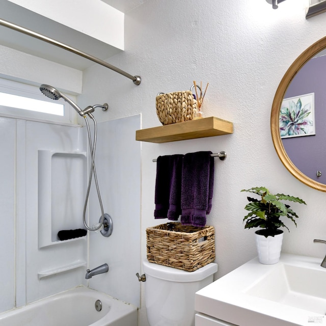bathroom with a textured wall, bathing tub / shower combination, toilet, and vanity