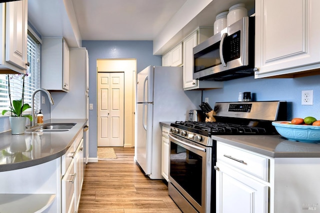 kitchen with dark countertops, white cabinetry, appliances with stainless steel finishes, and a sink