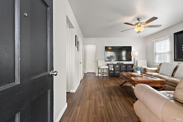 living area featuring a ceiling fan, dark wood-style flooring, and baseboards