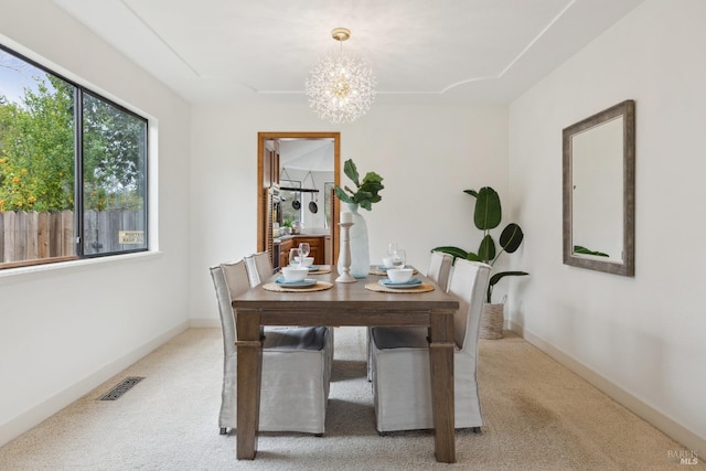 dining space featuring light carpet, baseboards, visible vents, and a notable chandelier