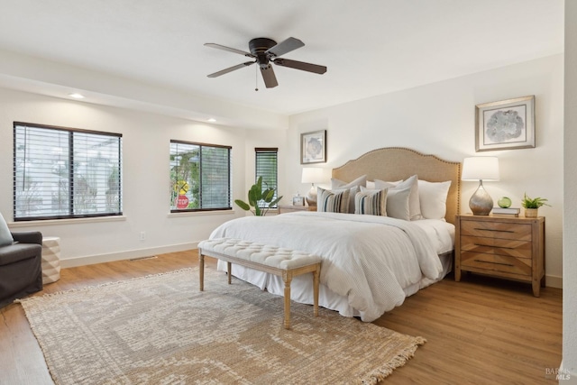 bedroom with light wood-style floors, ceiling fan, visible vents, and baseboards