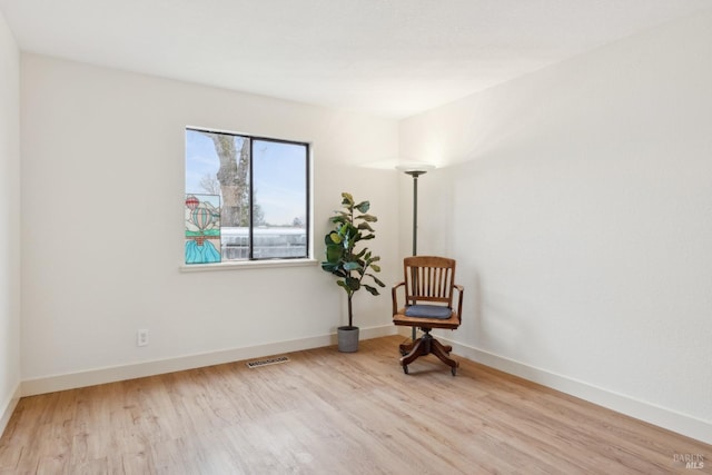 living area featuring light wood-type flooring, visible vents, and baseboards