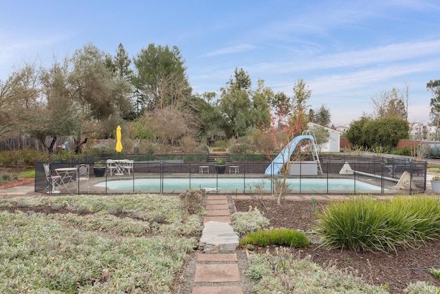 view of swimming pool with a water slide and fence