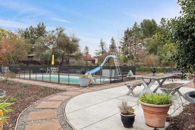 view of swimming pool featuring a fenced in pool, a water slide, fence, and a patio