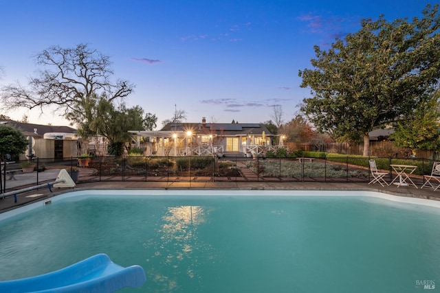 pool at dusk featuring fence and a fenced in pool