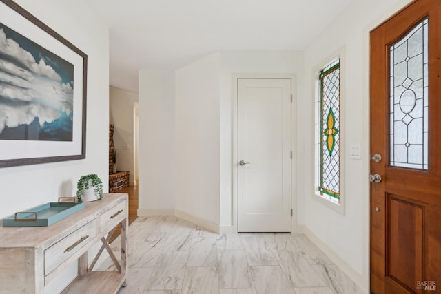 entryway featuring marble finish floor, stairway, and baseboards