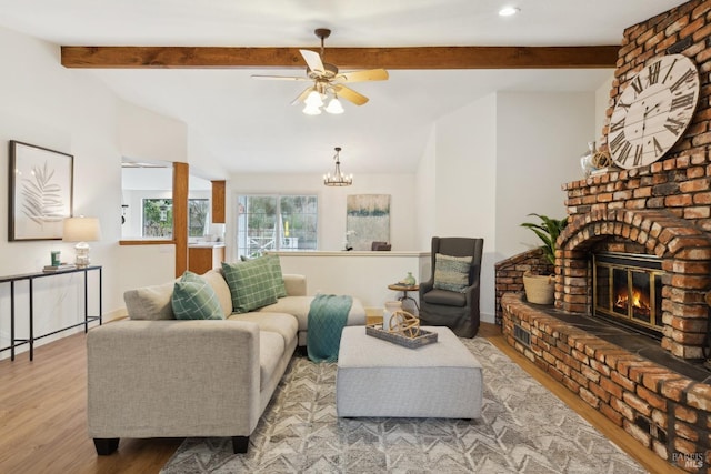 living area with light wood finished floors, baseboards, lofted ceiling with beams, a fireplace, and ceiling fan with notable chandelier