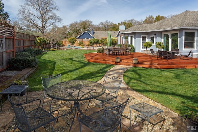 view of yard featuring a fenced backyard, a deck, and outdoor dining area