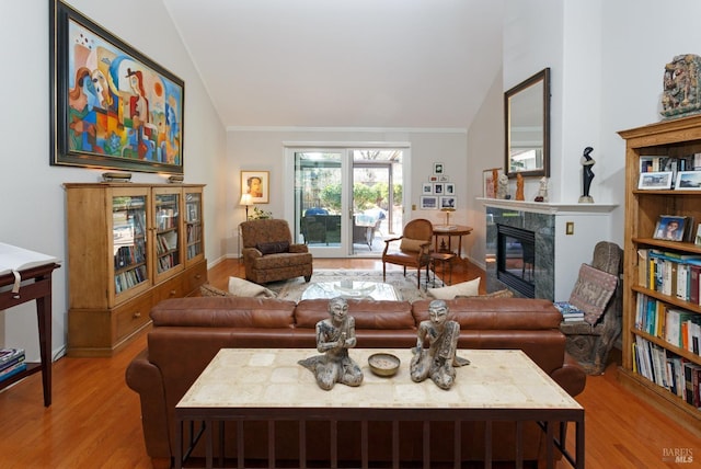 living room with vaulted ceiling, ornamental molding, a fireplace, and wood finished floors