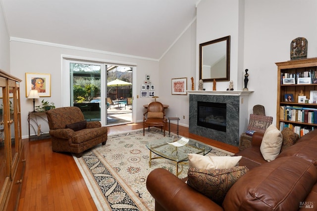 living room featuring ornamental molding, wood-type flooring, vaulted ceiling, and a premium fireplace