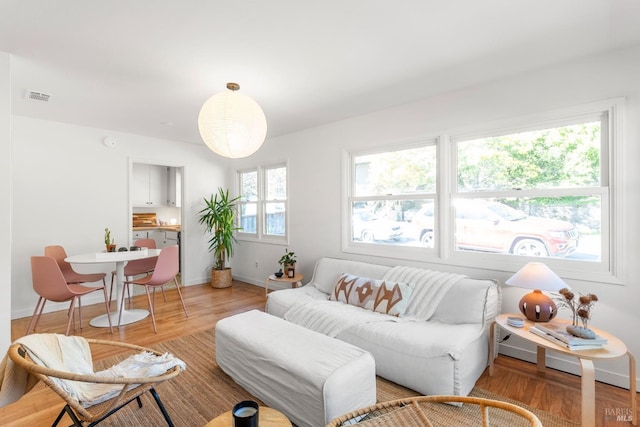 living area featuring baseboards, visible vents, and wood finished floors