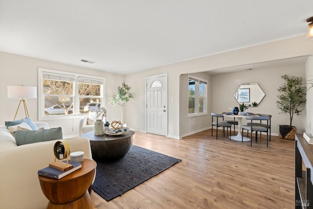 living room featuring visible vents, light wood-style flooring, and baseboards