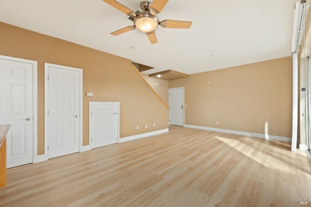 unfurnished living room featuring ceiling fan, baseboards, and light wood-style floors