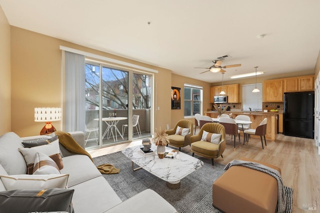 living area featuring visible vents, ceiling fan, and light wood-style floors