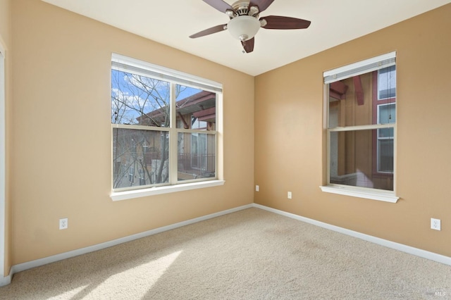 carpeted empty room featuring ceiling fan and baseboards