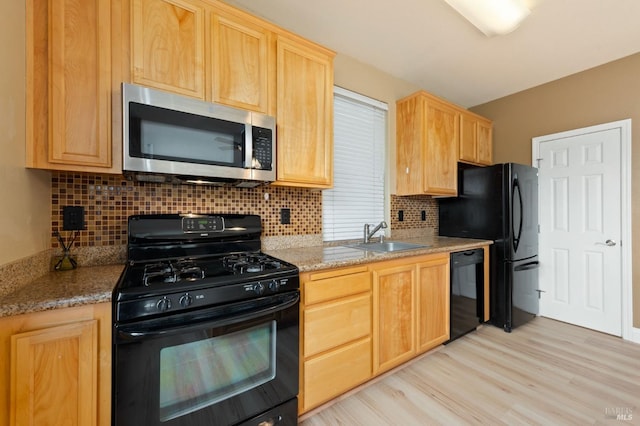 kitchen with black appliances, light brown cabinetry, a sink, backsplash, and light wood finished floors