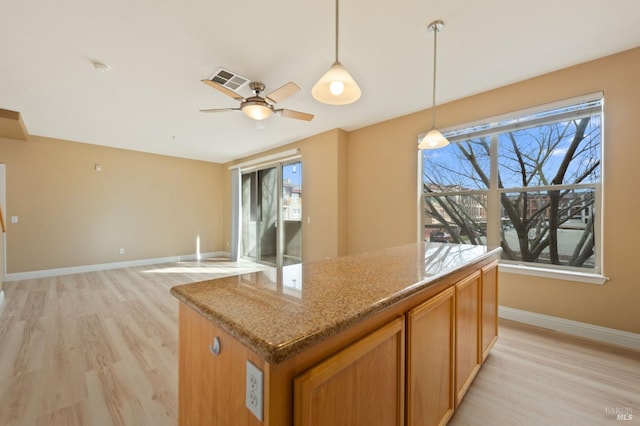kitchen featuring light stone countertops, baseboards, visible vents, pendant lighting, and light wood-type flooring