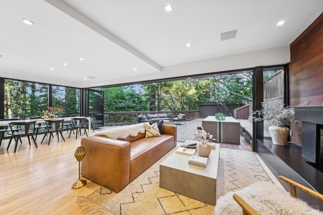 living room featuring a glass covered fireplace, floor to ceiling windows, light wood-style flooring, and recessed lighting