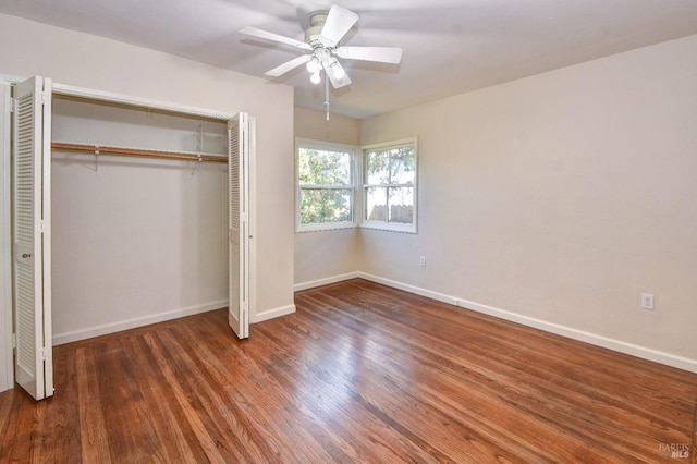 unfurnished bedroom with dark wood-style floors, a closet, and baseboards