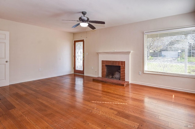 unfurnished living room with ceiling fan, a fireplace, baseboards, and hardwood / wood-style flooring