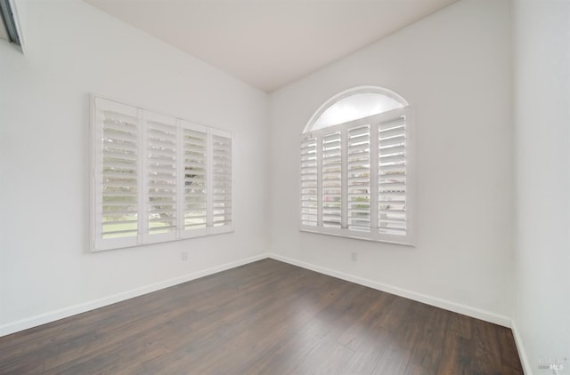 spare room featuring dark wood-style floors and baseboards