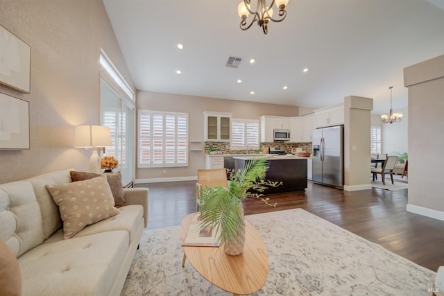 living room with dark wood finished floors, a notable chandelier, visible vents, high vaulted ceiling, and baseboards