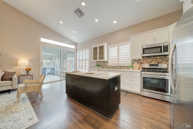 kitchen with appliances with stainless steel finishes, glass insert cabinets, visible vents, and white cabinets