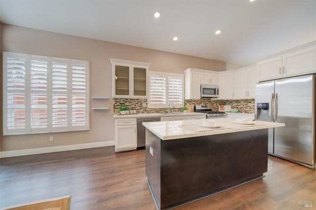 kitchen featuring a center island, stainless steel appliances, glass insert cabinets, white cabinetry, and a sink