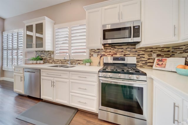 kitchen featuring a sink, white cabinetry, light countertops, appliances with stainless steel finishes, and glass insert cabinets