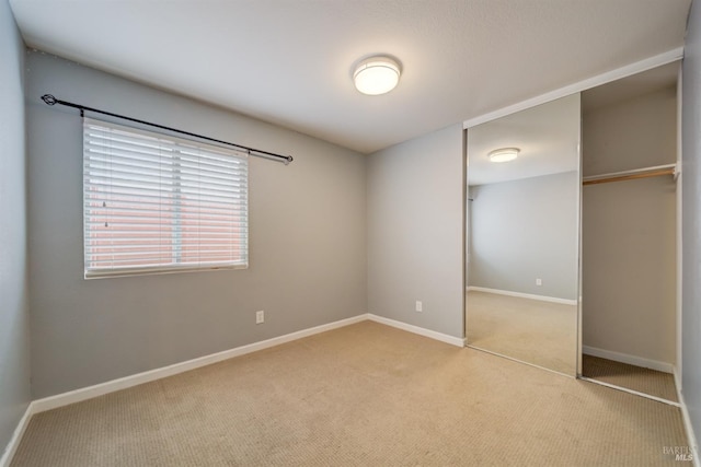 unfurnished bedroom with light carpet, baseboards, and a closet