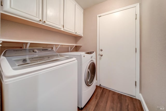 washroom with dark wood-style floors, cabinet space, and washer and dryer