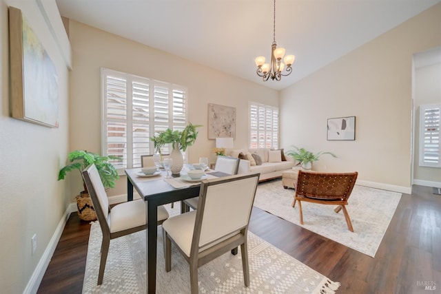 dining room featuring dark wood-type flooring, lofted ceiling, baseboards, and an inviting chandelier