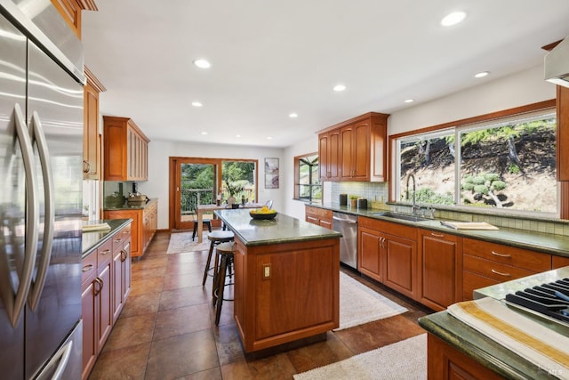 kitchen featuring dark countertops, appliances with stainless steel finishes, a sink, and a center island