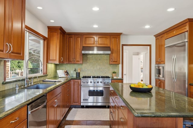 kitchen featuring built in appliances, a sink, range hood, a center island, and brown cabinetry